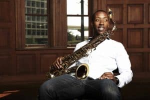 Musician Calvin Johnson sits in a chair with his saxophone on his lap
