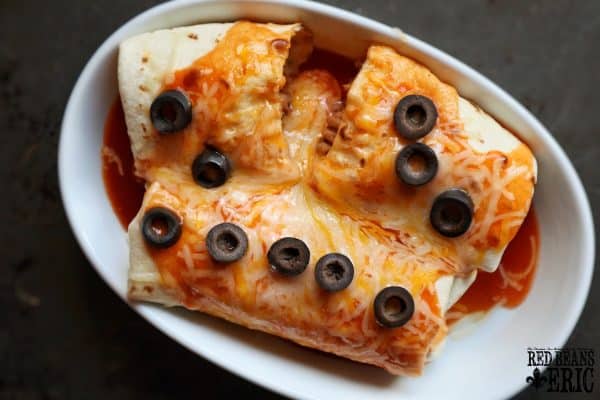 Plate of Enchiritos cut in half and topped with melted chaeddar cheese and black olives.
