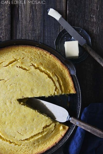 A skillet of cornbread with a slice removed.