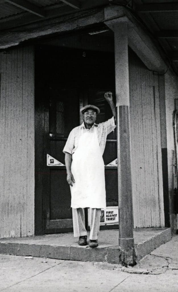 Buster Holmes leaning in doorway to his restaurant.